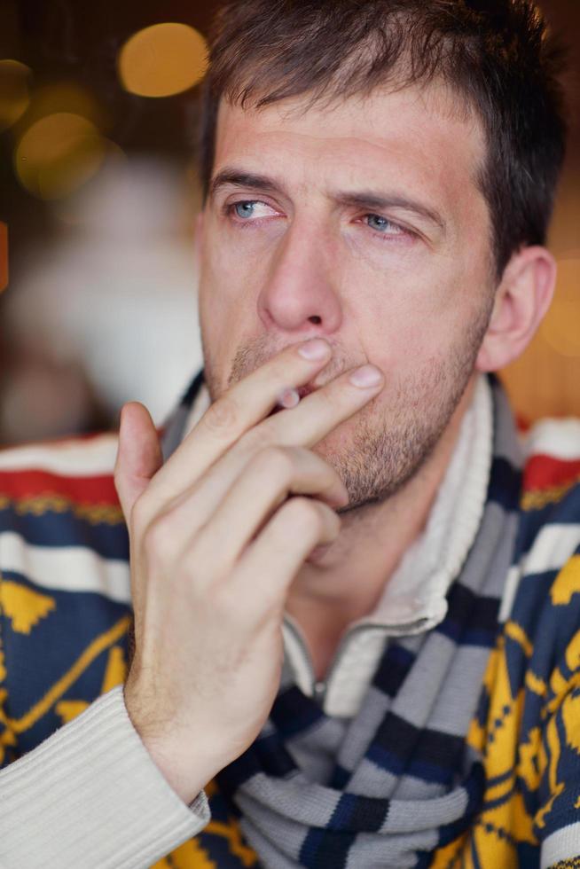 homem fuma um cigarro contra um fundo escuro foto