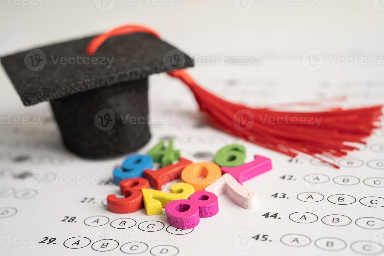 número de matemática colorido com chapéu de formatura e lápis no fundo da folha de respostas, educação estudo matemática aprendizagem ensinar conceito. foto
