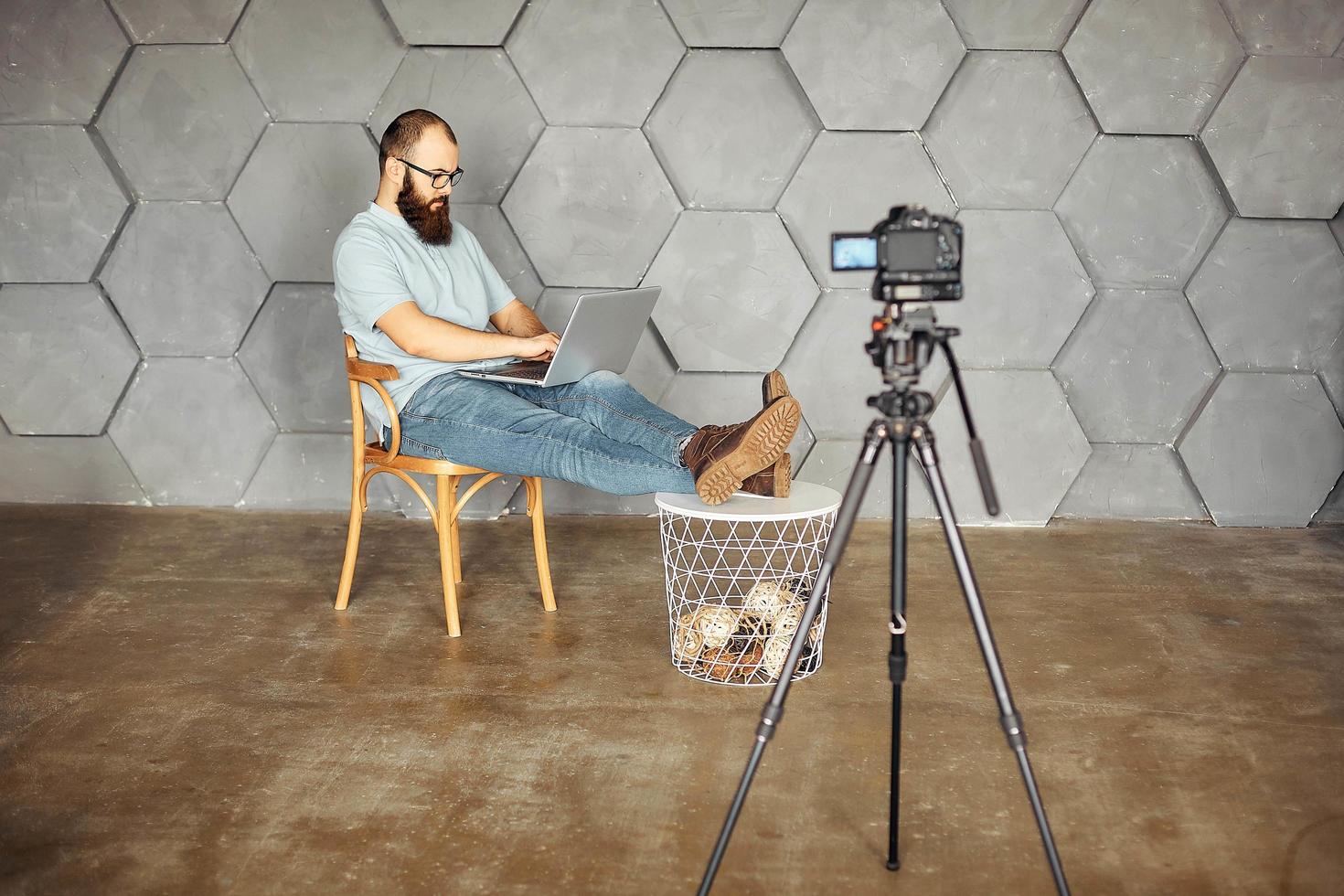 criação de conteúdo para redes sociais. homem barbudo gravando vídeo de si mesmo usando a câmera no tripé. tecnologia moderna e conceito de trabalho freelance de blogs. foto