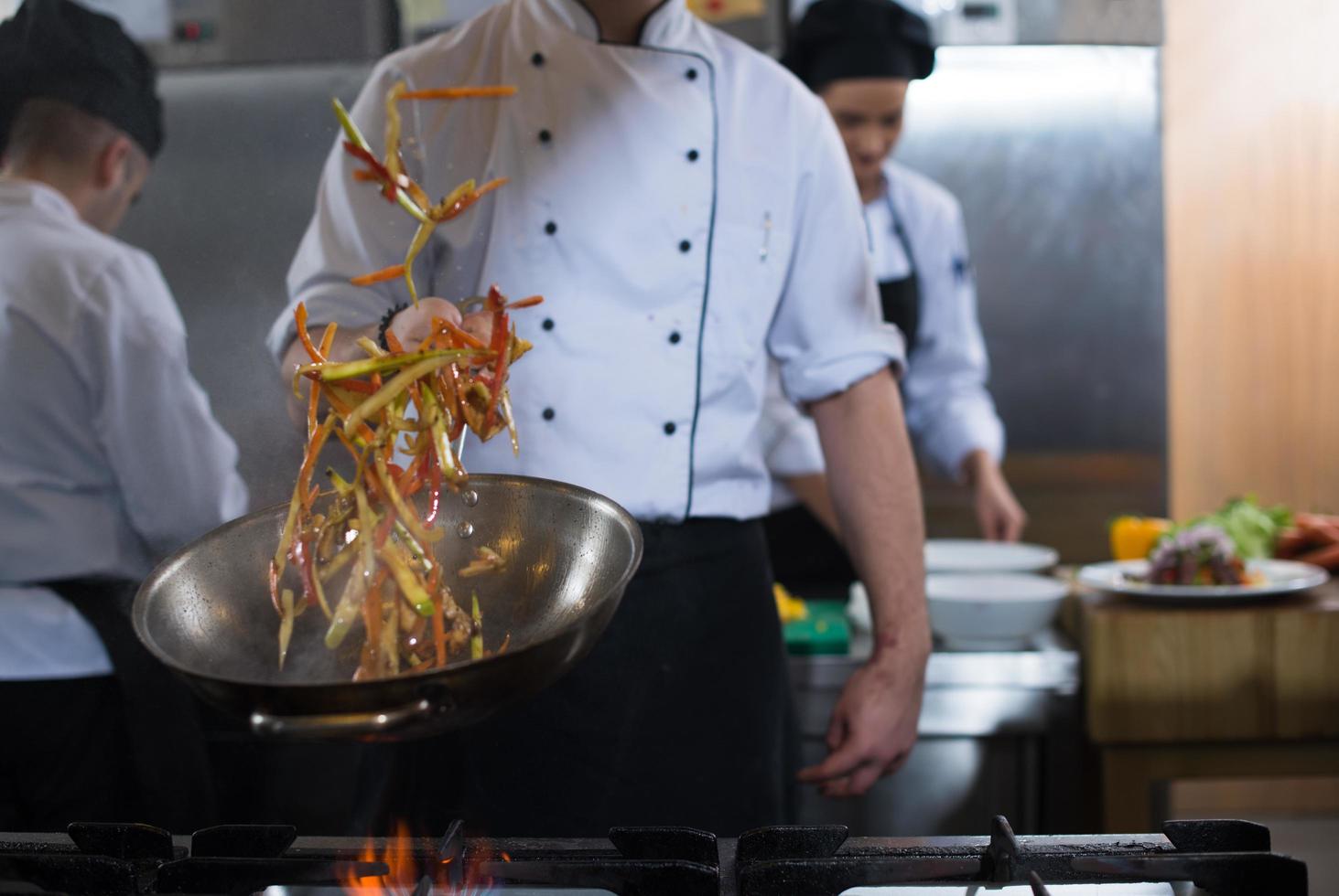 chef lançando legumes no wok foto