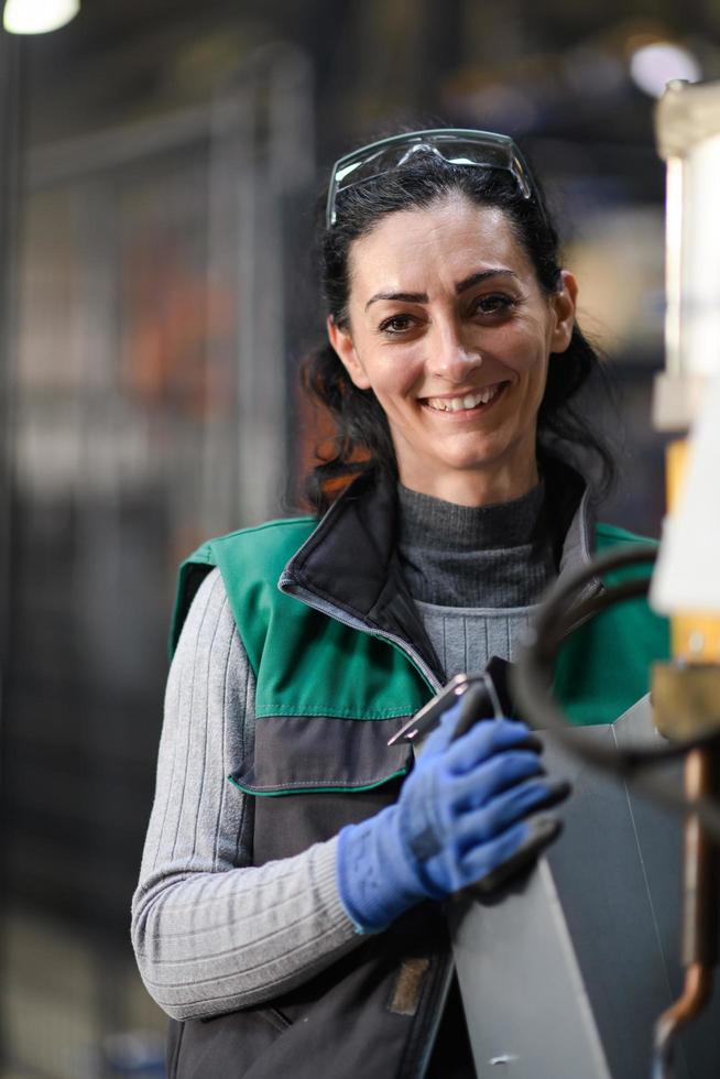 uma mulher que trabalha em uma fábrica de metal moderna monta peças para uma nova máquina foto