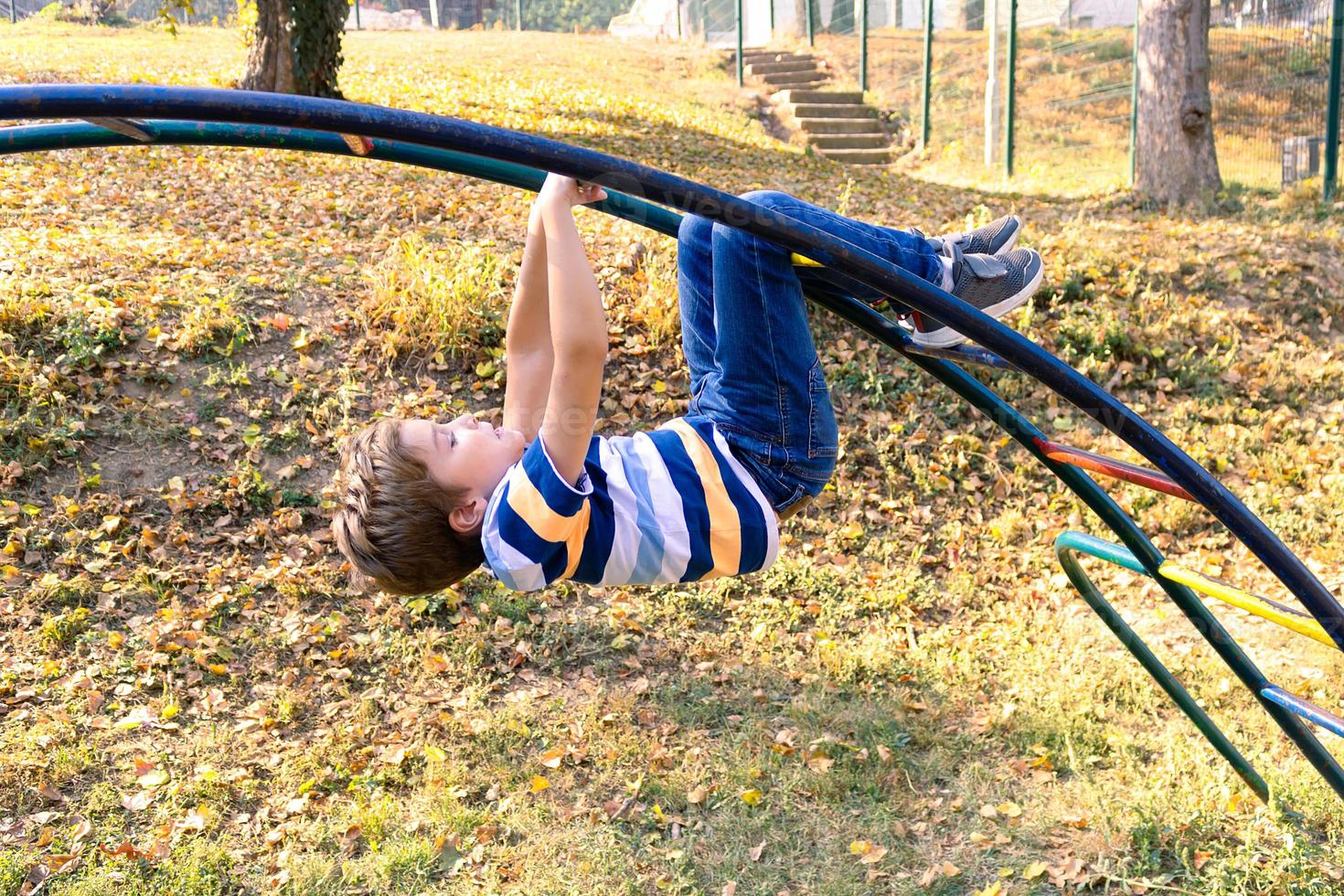 menino despreocupado brincando no playground na natureza. foto