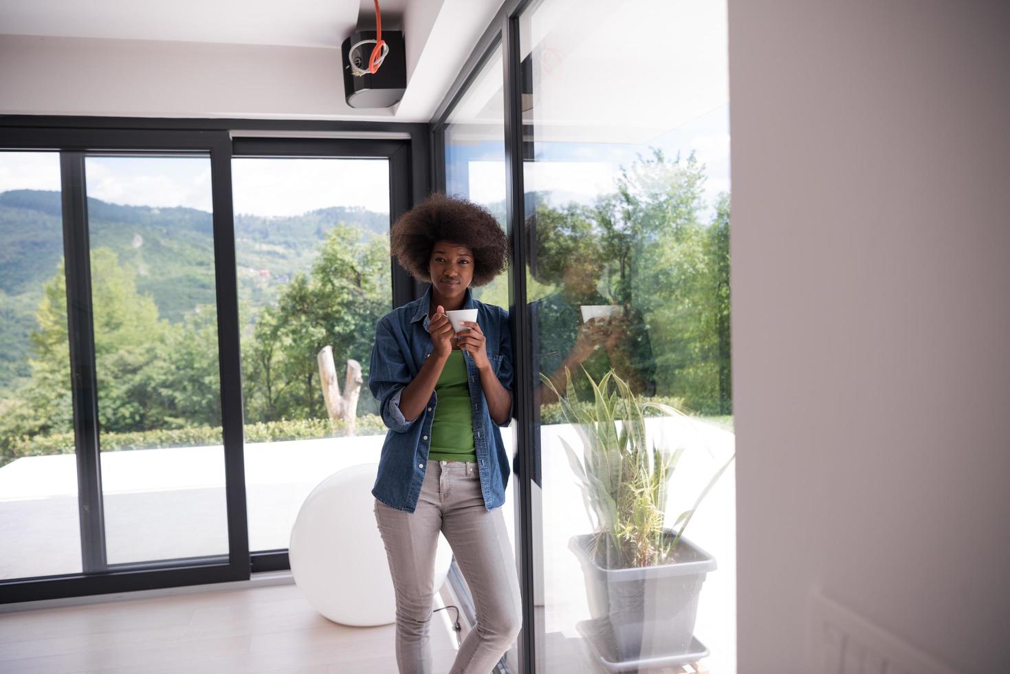 mulher afro-americana tomando café olhando pela janela foto