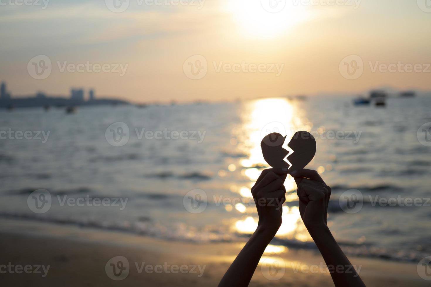 duas mãos segurando a forma de coração partido com fundo por do sol, conceito de plano de fundo silhueta dia dos namorados foto