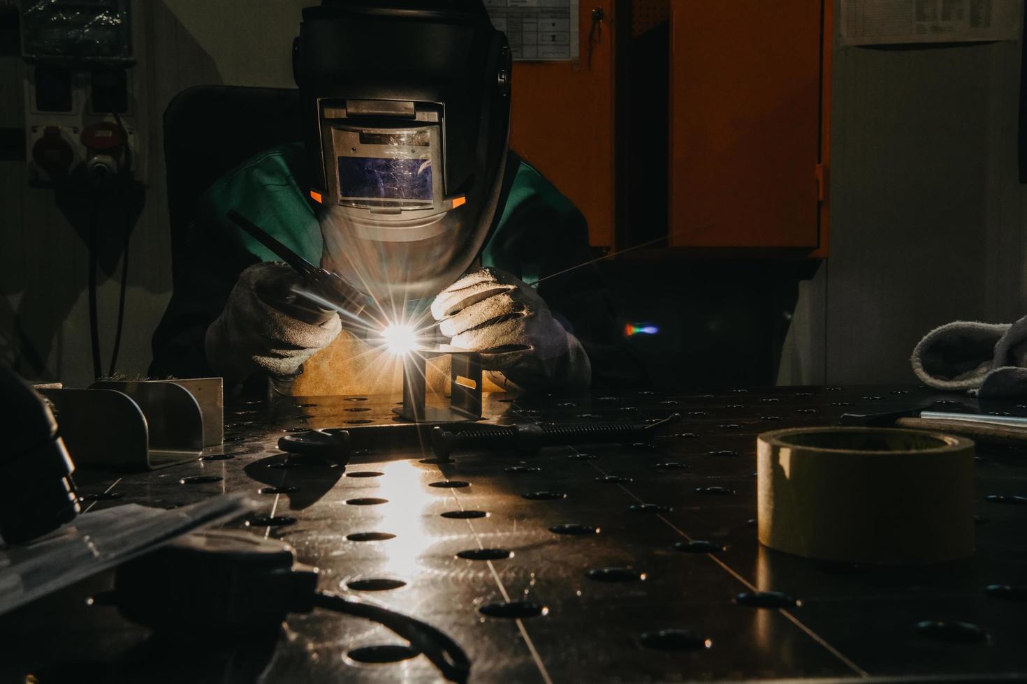 uma mulher empregada em uma fábrica moderna para a produção e processamento de metais em um trabalho uniforme de soldagem de materiais metálicos foto