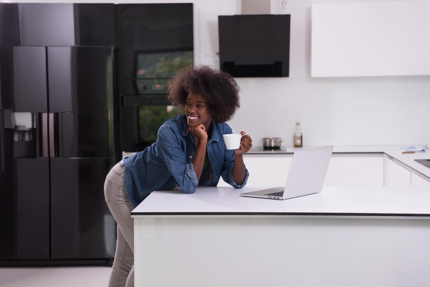 mulher negra sorridente na cozinha moderna foto