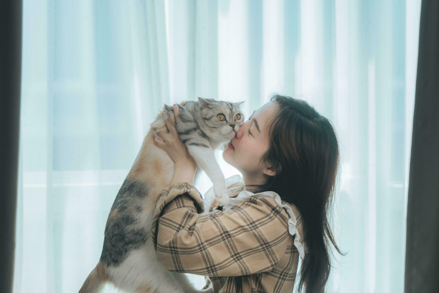 closeup retrato bonito jovem hipster, abraça seu bom amigo ruivo gato no fundo da parede branca. emoções humanas positivas, expressão facial, sentimentos. pessoas e animais apaixonados foto