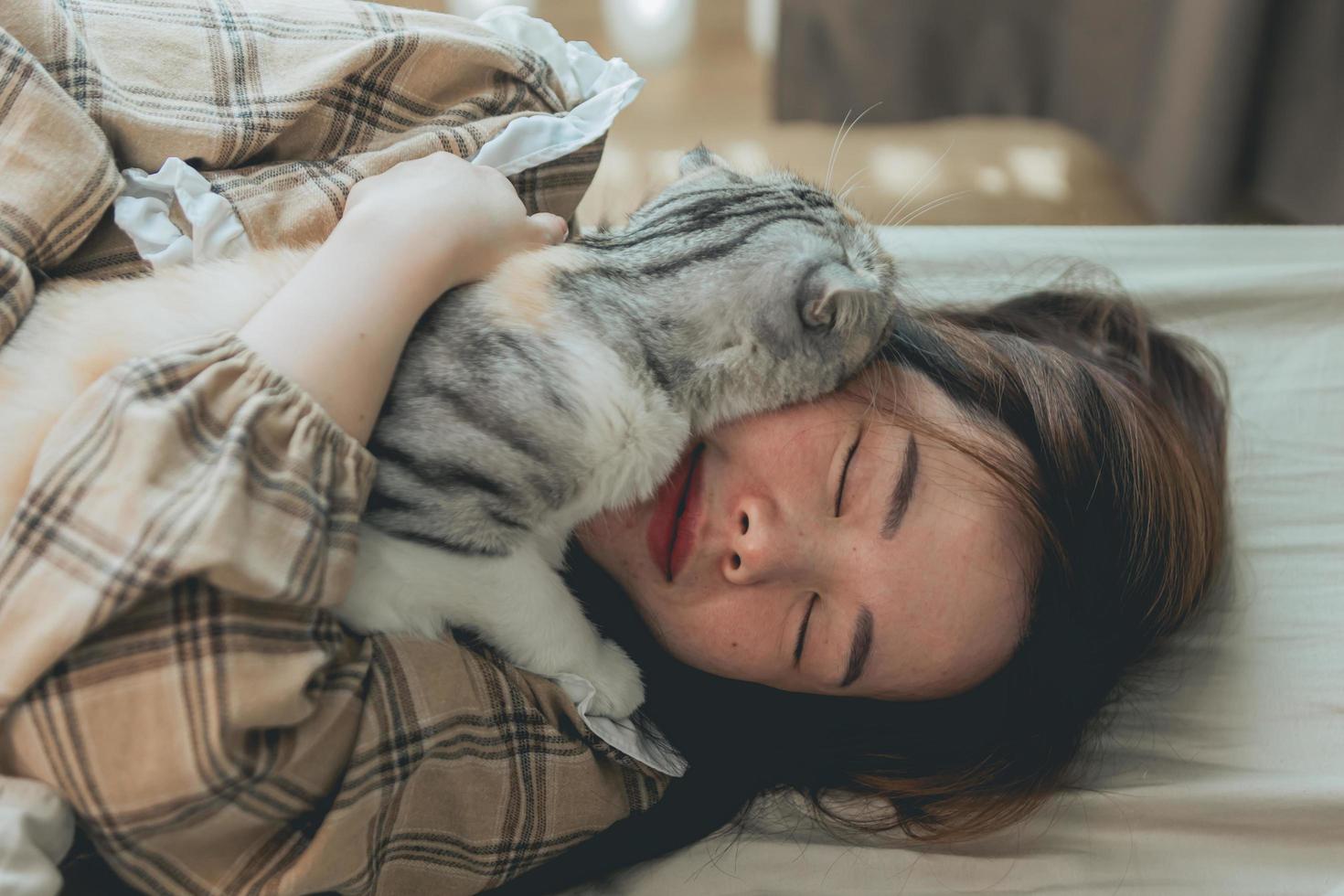 feliz sorriso asiático mulheres abraçando gato bonito em casa. foto