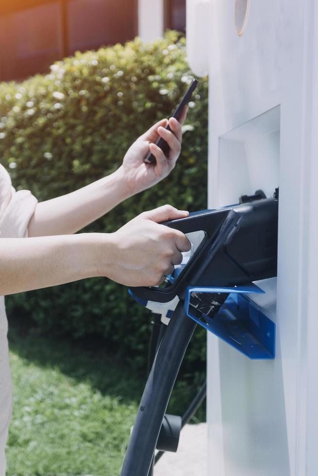 mão conectando um carregador em uma tomada de carro elétrico. carro elétrico ou ev está carregando na estação foto