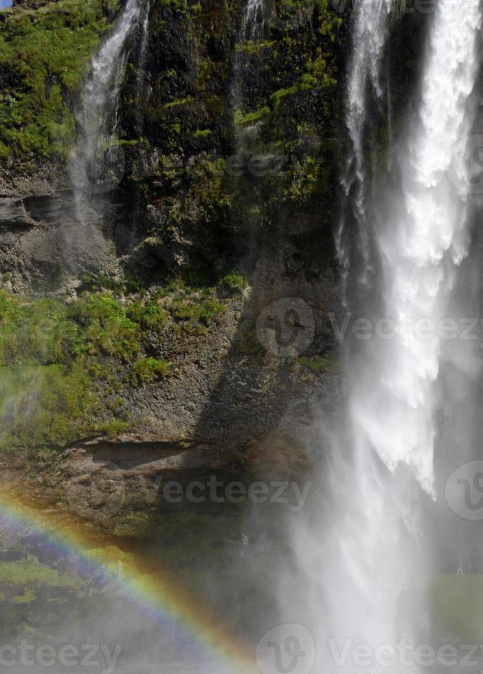 um arco-íris na frente da cachoeira seljalandsfoss na costa sul da islândia em um dia ensolarado foto