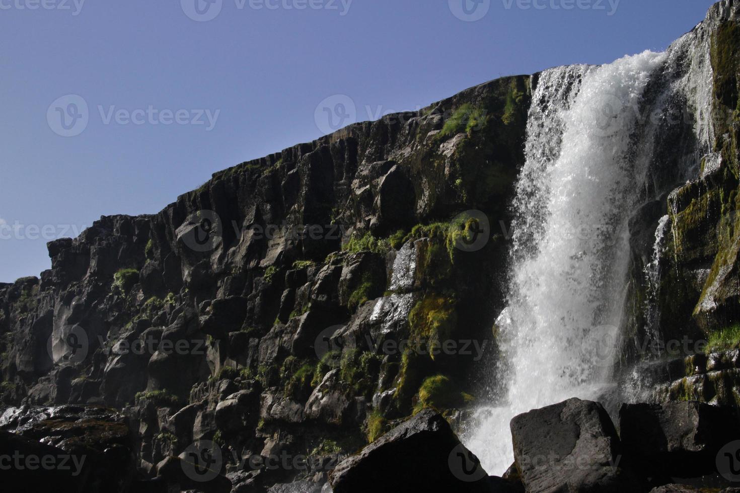 uma grande cachoeira sobre um penhasco rochoso - oxarafoss no parque nacional thingvellir. foto