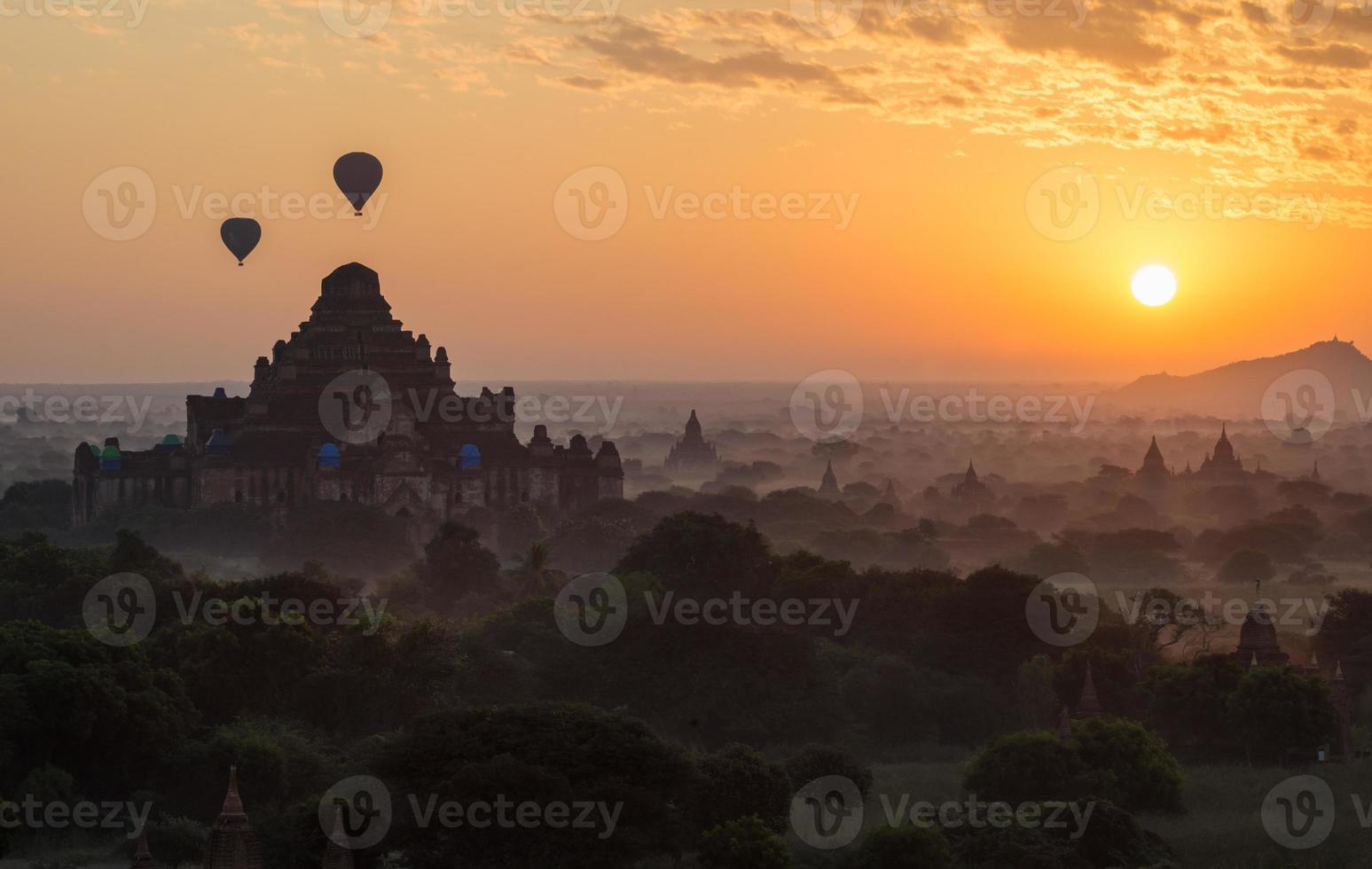 balões de ar quente sobrevoam o templo dhammayangyi, o maior templo das planícies de bagan, durante o nascer do sol da manhã em mianmar. foto