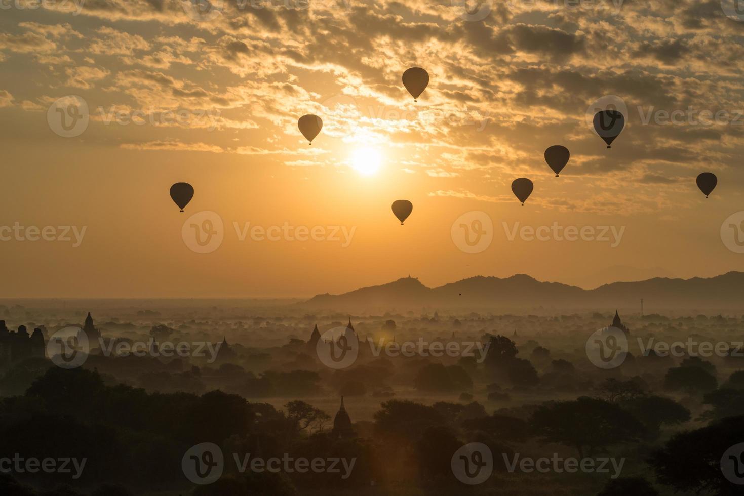 balões de ar quente sobrevoam as planícies de bagan durante o nascer do sol da manhã em mianmar. foto