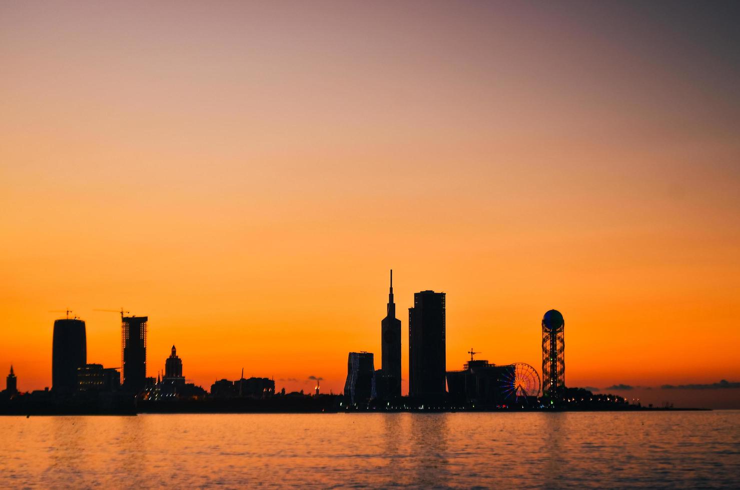 impressionantes silhuetas dramáticas de marcos da arquitetura da cidade de batumi com fundo por do sol. destino de viagem na geórgia foto