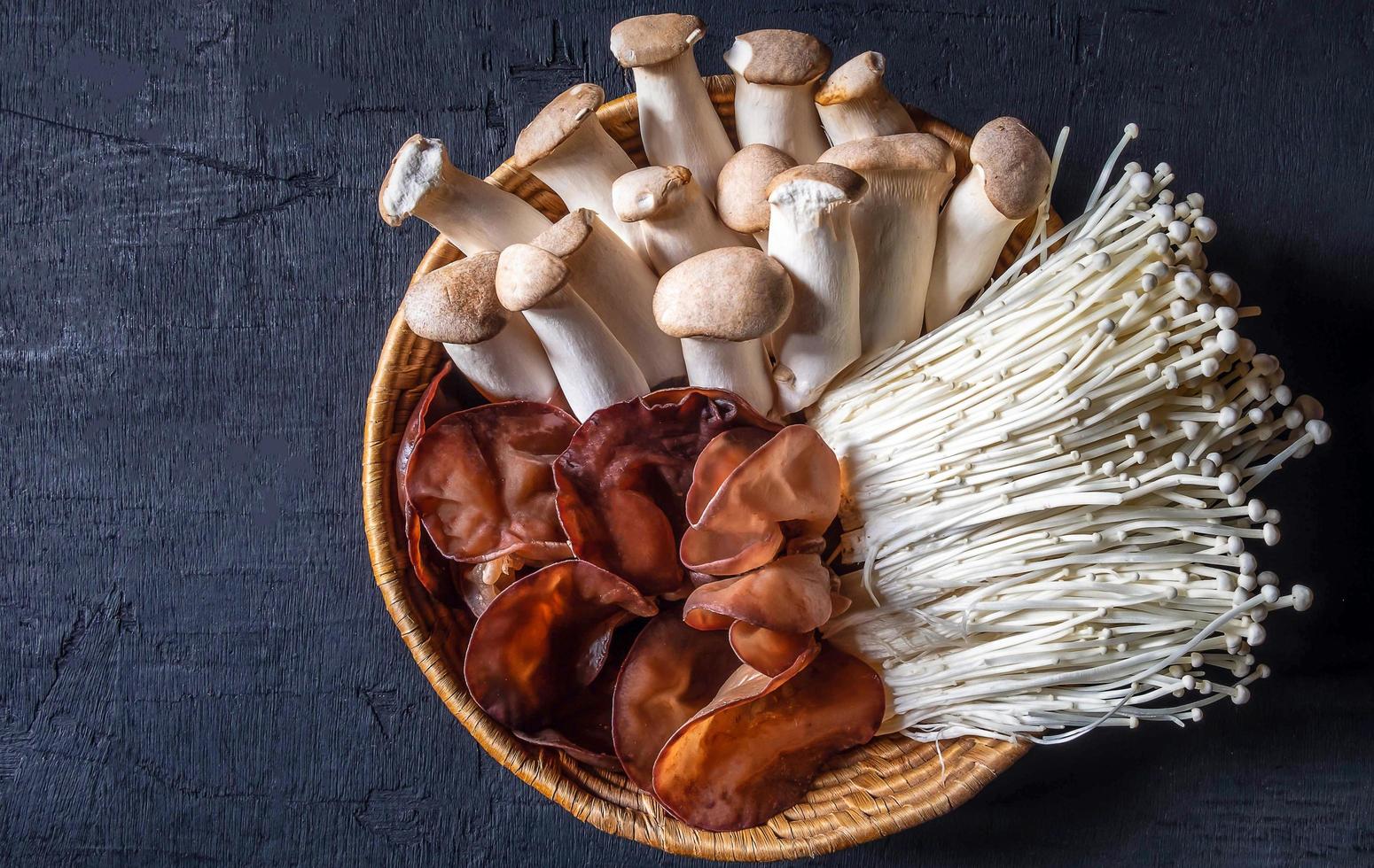 vista superior do cogumelo de orelha ou fungo de geléia preta, cogumelo de agulha dourada, cogumelo de ostra real na cesta de madeira v foto