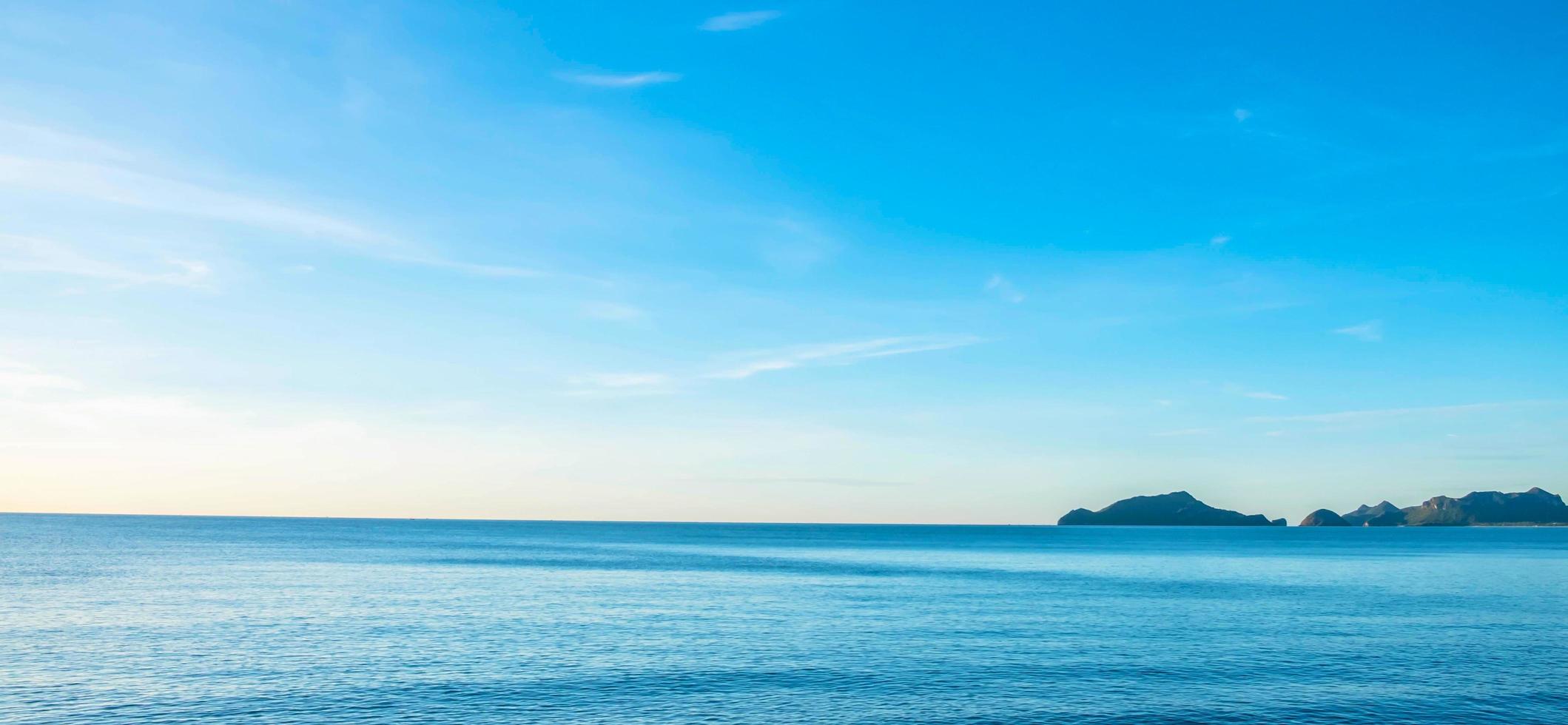 a vista do mar de manhã com os raios dourados do sol brilhando no mar no verão foto