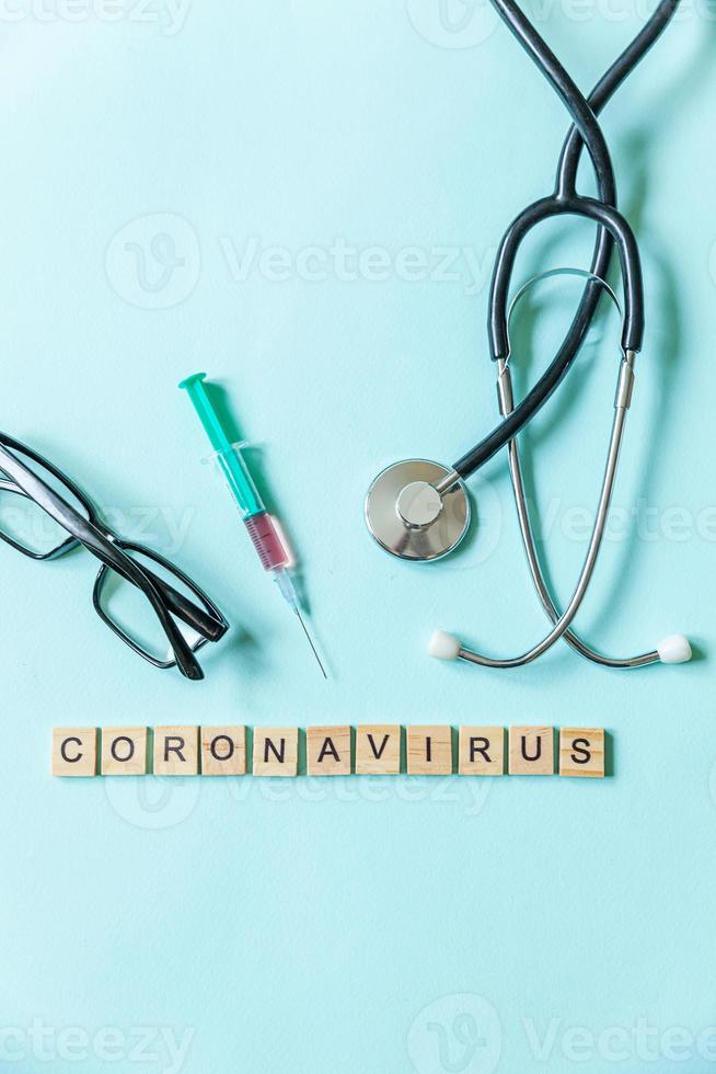 frase de texto óculos de seringa coronavírus e estetoscópio em fundo azul pastel. novo coronavírus 2019-ncov mers-cov covid-19 síndrome respiratória do oriente médio conceito de vacina contra vírus coronavírus. foto