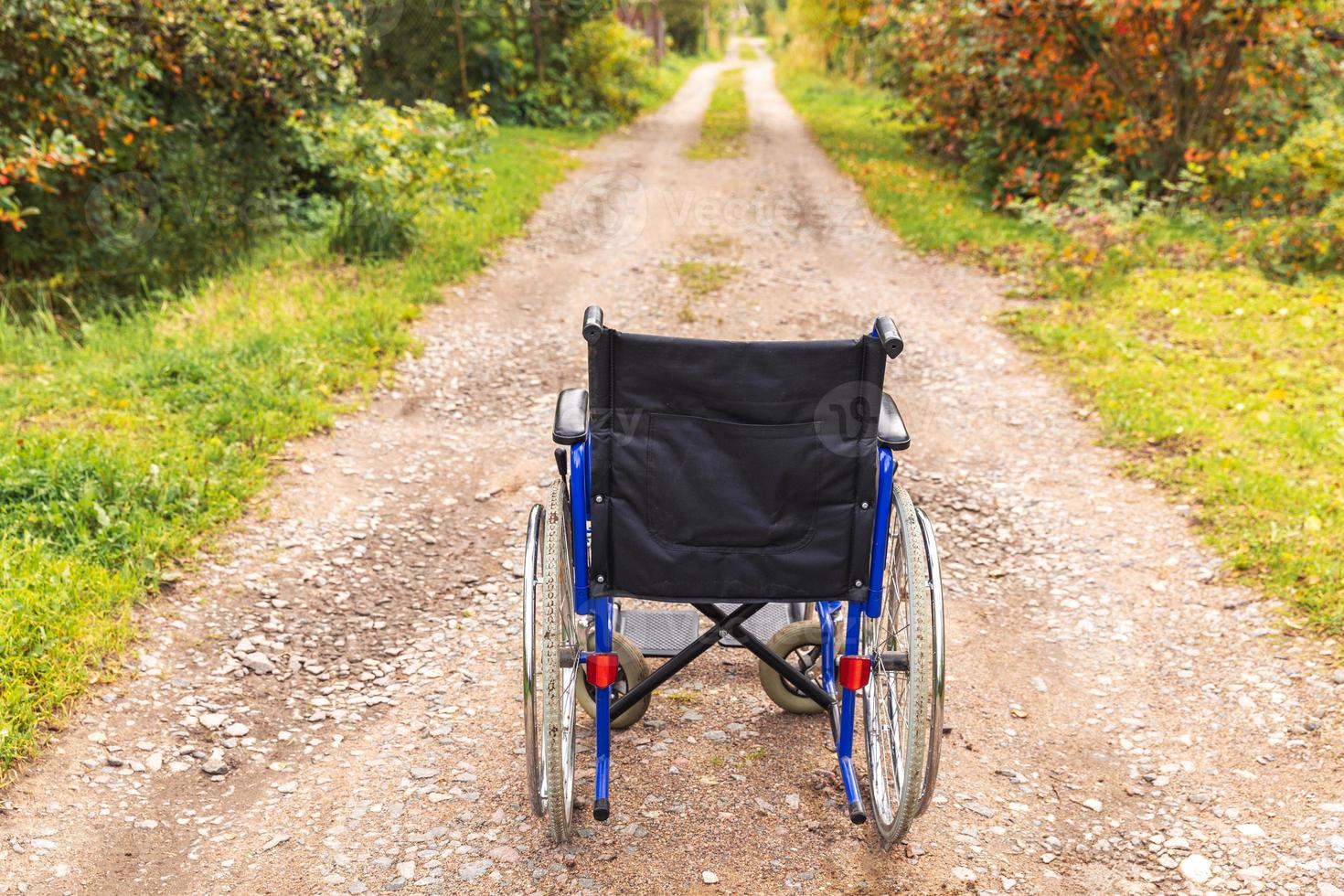 cadeira de rodas vazia em pé na estrada à espera de serviços ao paciente. cadeira de rodas para pessoas com deficiência estacionada ao ar livre. acessível para pessoa com deficiência. conceito médico de cuidados de saúde. foto