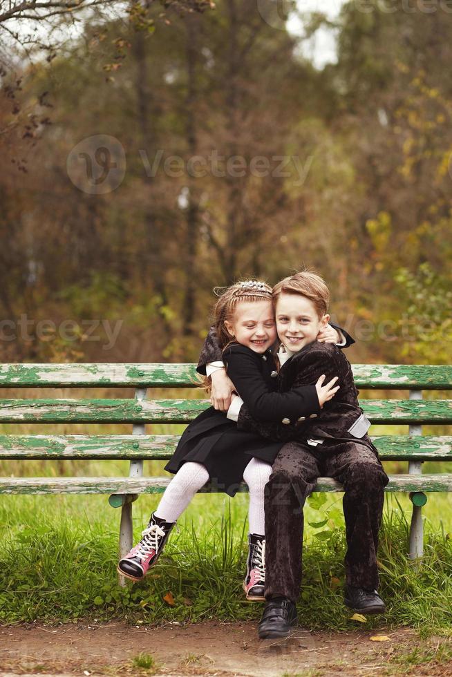 irmão e irmã crianças abraçando em um banco foto