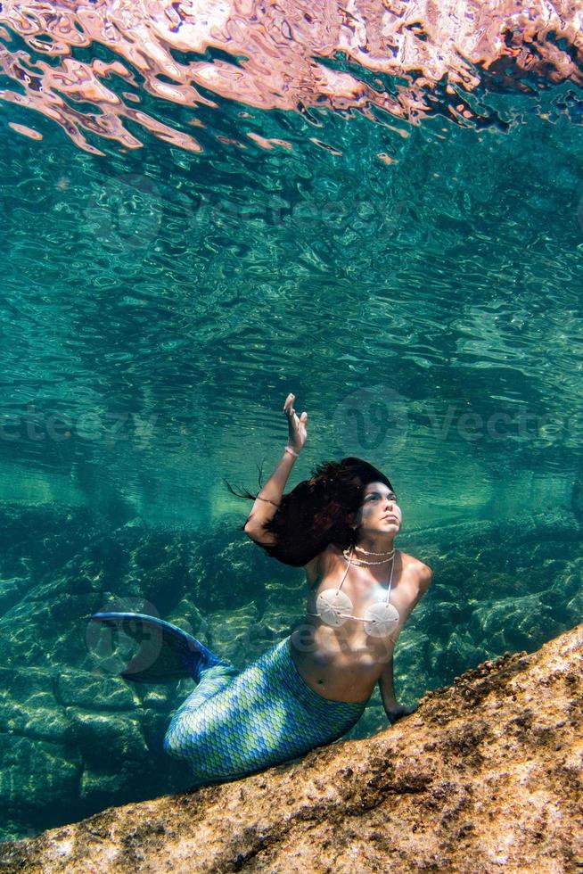 sereia nadando debaixo d'água no mar azul profundo foto