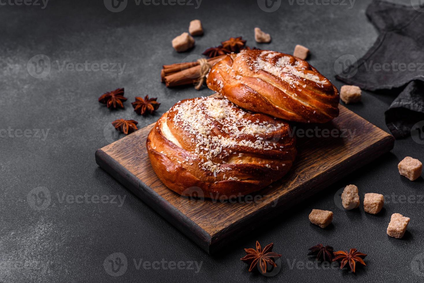 deliciosos pães de canela crocantes frescos polvilhados com migalhas de coco em uma tábua de madeira foto