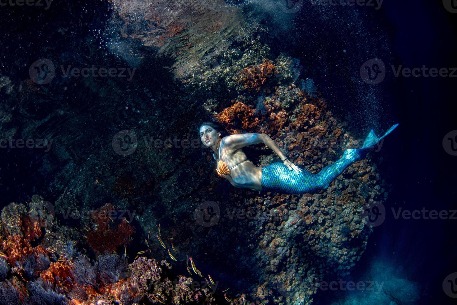 sereia nadando debaixo d'água no mar azul profundo foto