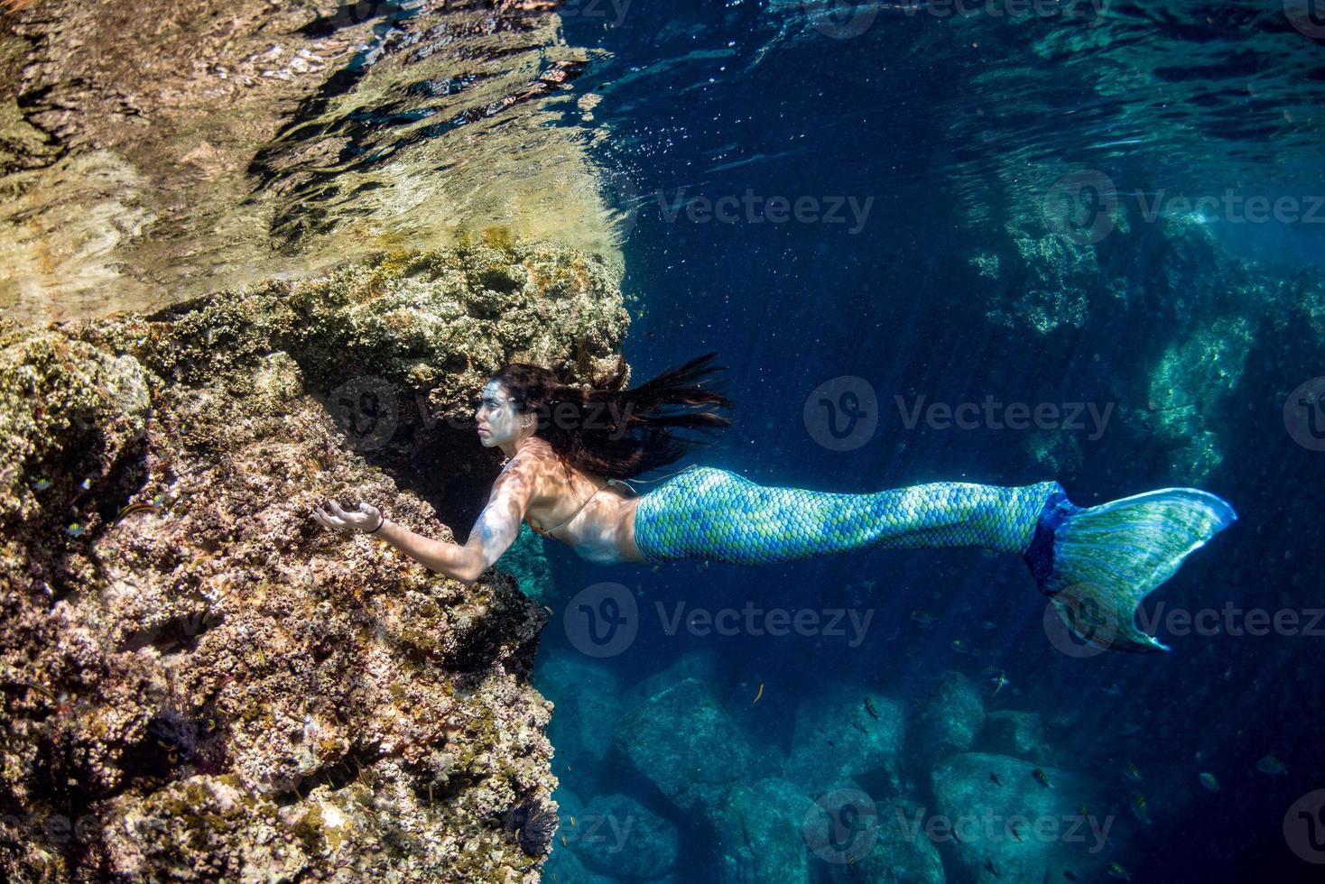 sereia nadando debaixo d'água no mar azul profundo foto