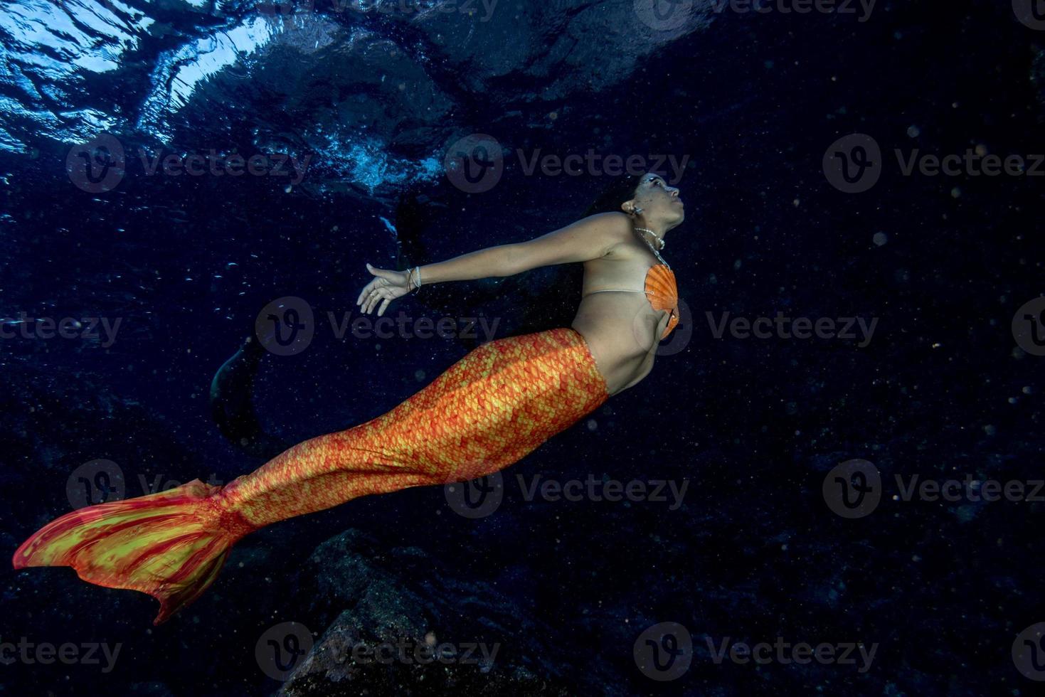 sereia nadando debaixo d'água no mar azul profundo foto