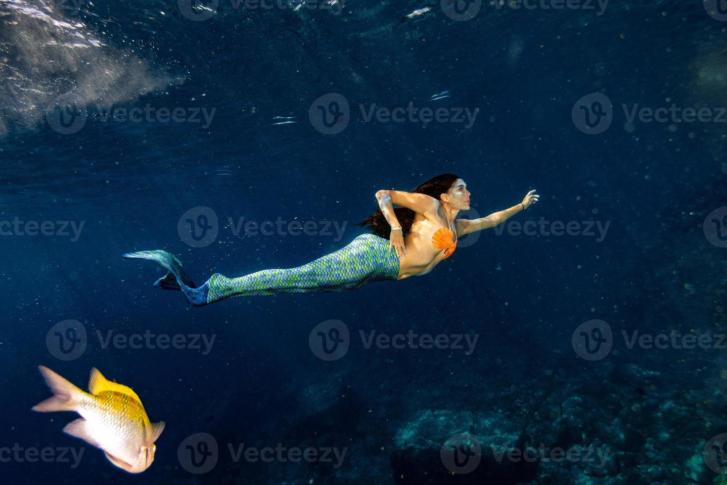 sereia nadando debaixo d'água no mar azul profundo foto