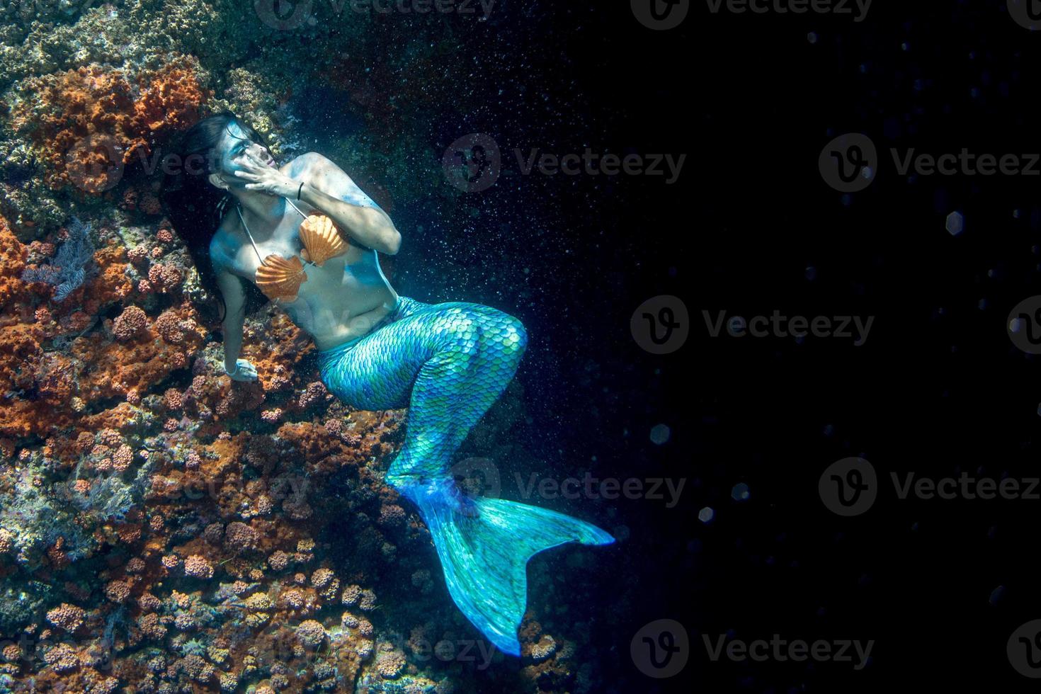 bela sereia nadando debaixo d'água no mar azul profundo foto