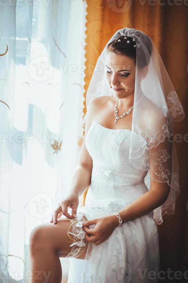 noiva linda se preparando no vestido de casamento branco com penteado foto