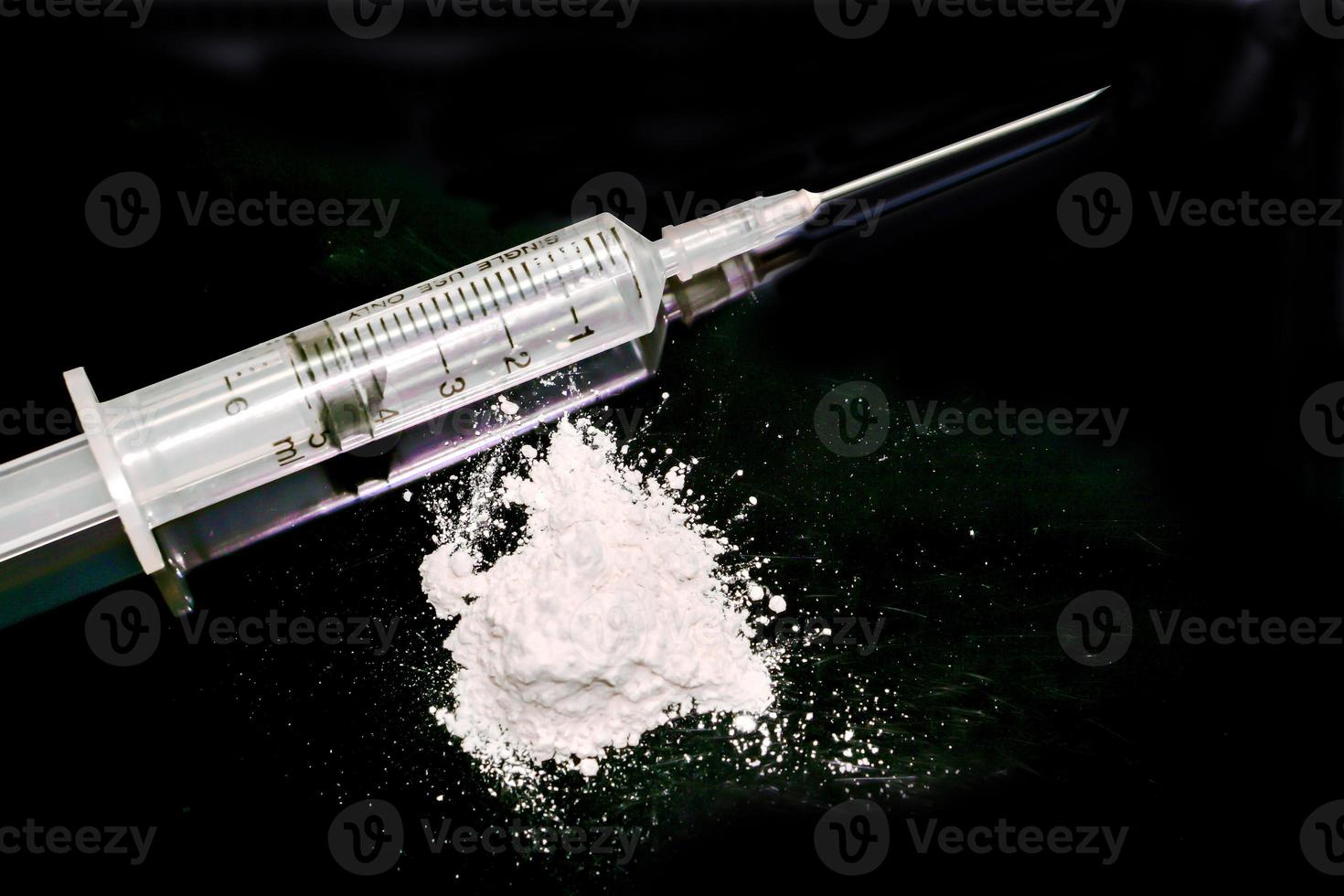 seringa de plástico colocada em uma agulha médica e pó branco isolado em fundo preto. suponho que a heroína ou vício em narcóticos. foto