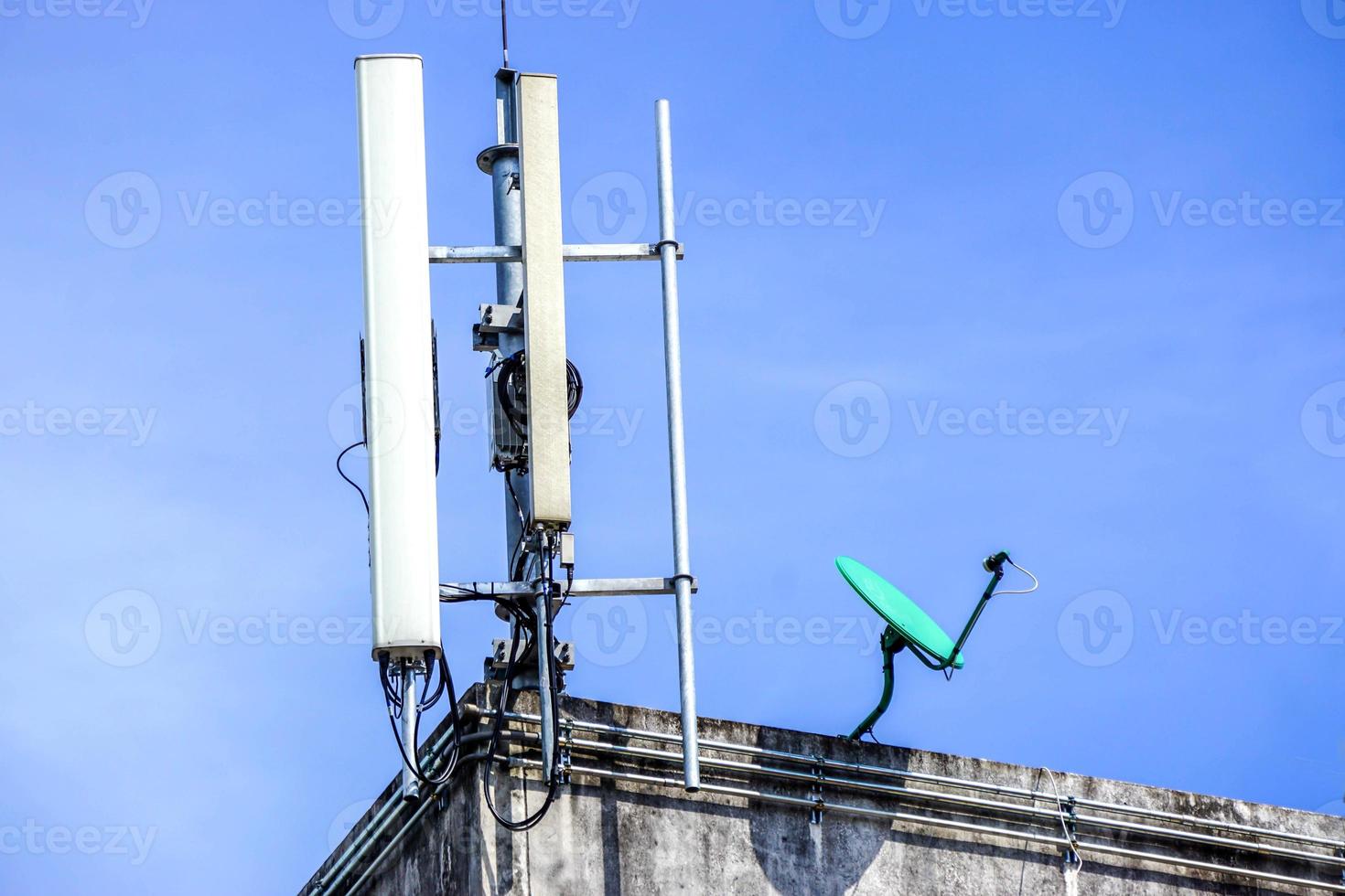 sinal de comunicação de dispositivos e receptores com antenas na parte superior do edifício e fundo de céu azul brilhante. foto