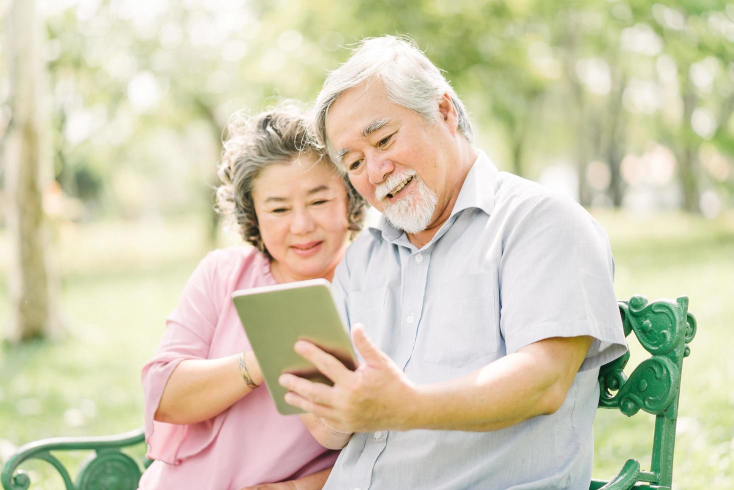 casal asiático sênior usando tablet no parque foto