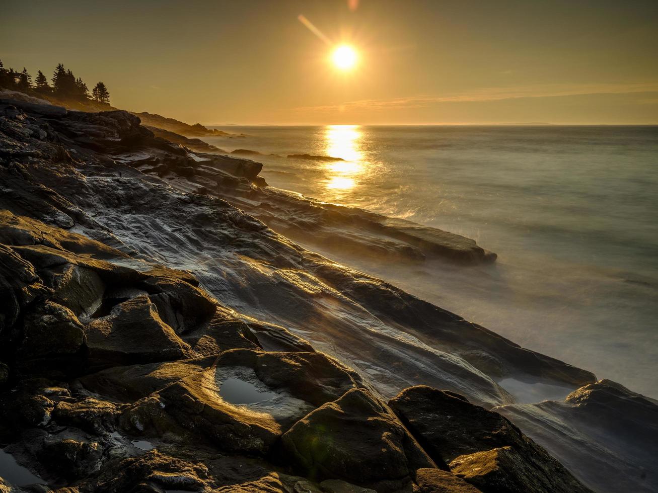 longa exposição das ondas do mar na praia rochosa foto