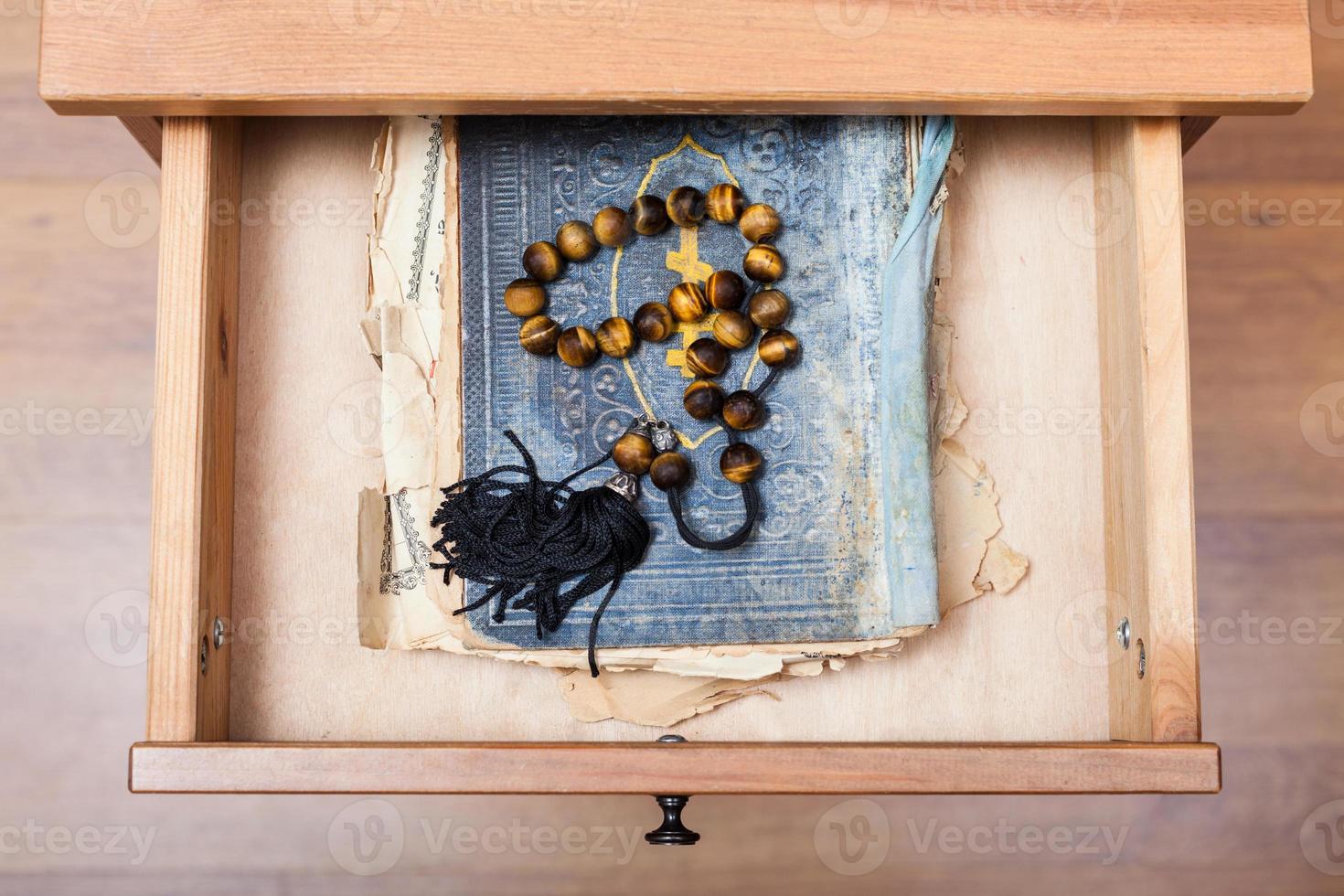 Rosário no velho livro religioso na gaveta aberta foto