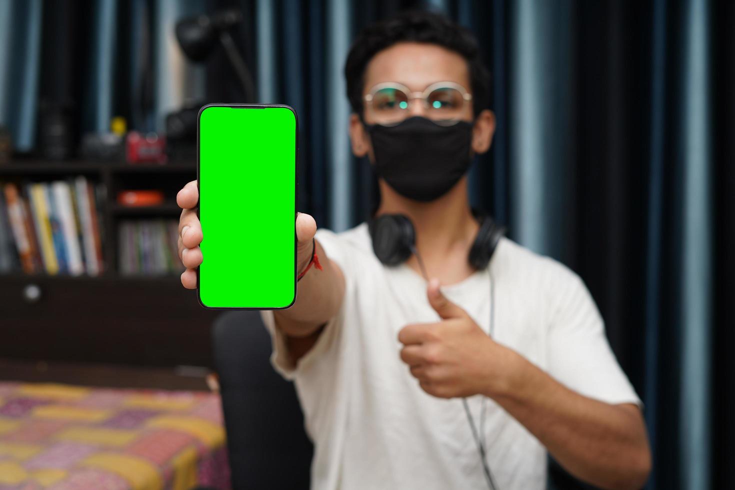 jovem rapaz indiano, segurando um telefone com tela verde foto