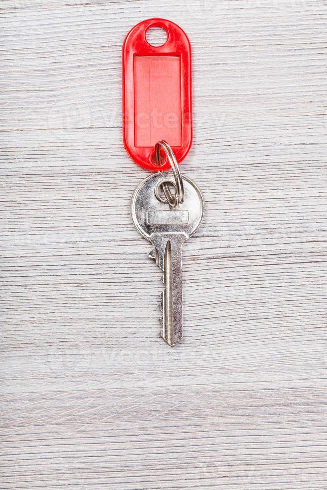 chave com chaveiro vermelho em branco na mesa de madeira foto