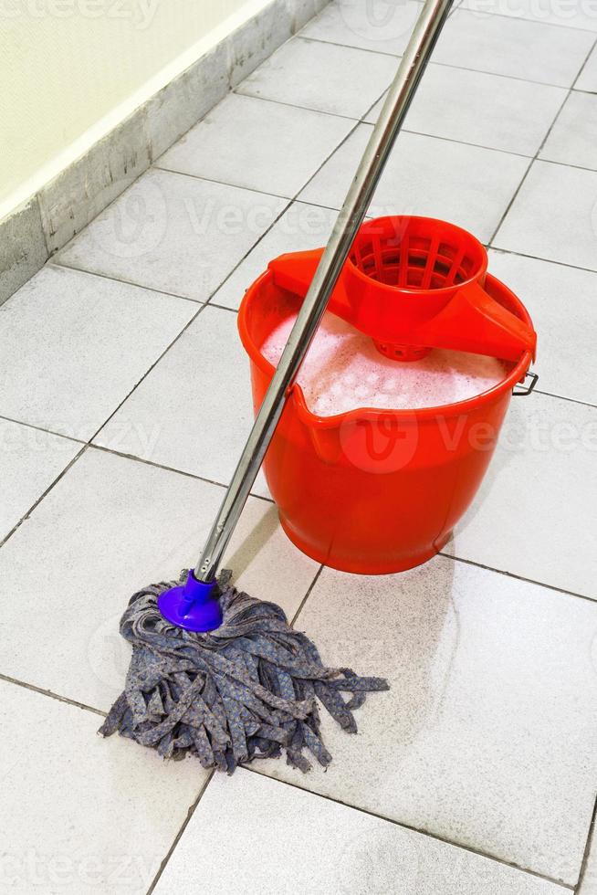 balde vermelho com água de lavagem e esfregue o chão foto