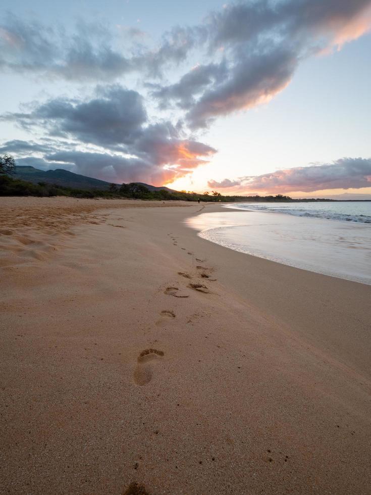 pegadas na praia durante o pôr do sol foto