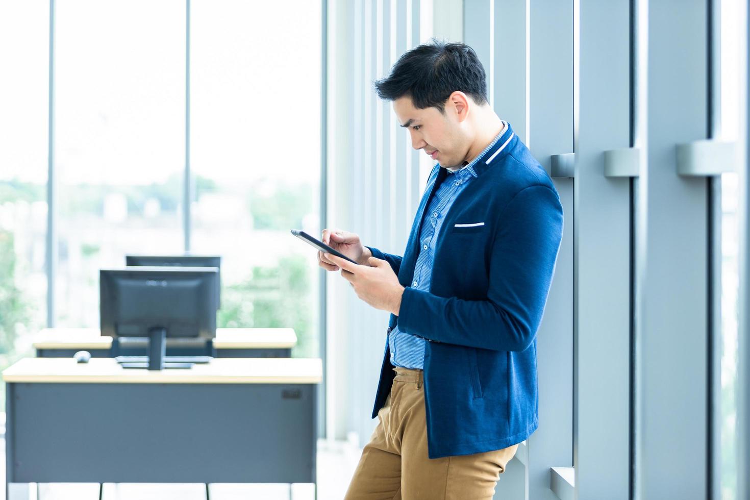 jovem empresário asiático usando tablet móvel no trabalho foto