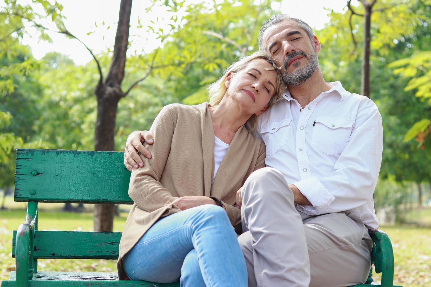 casal relaxando no banco do parque foto