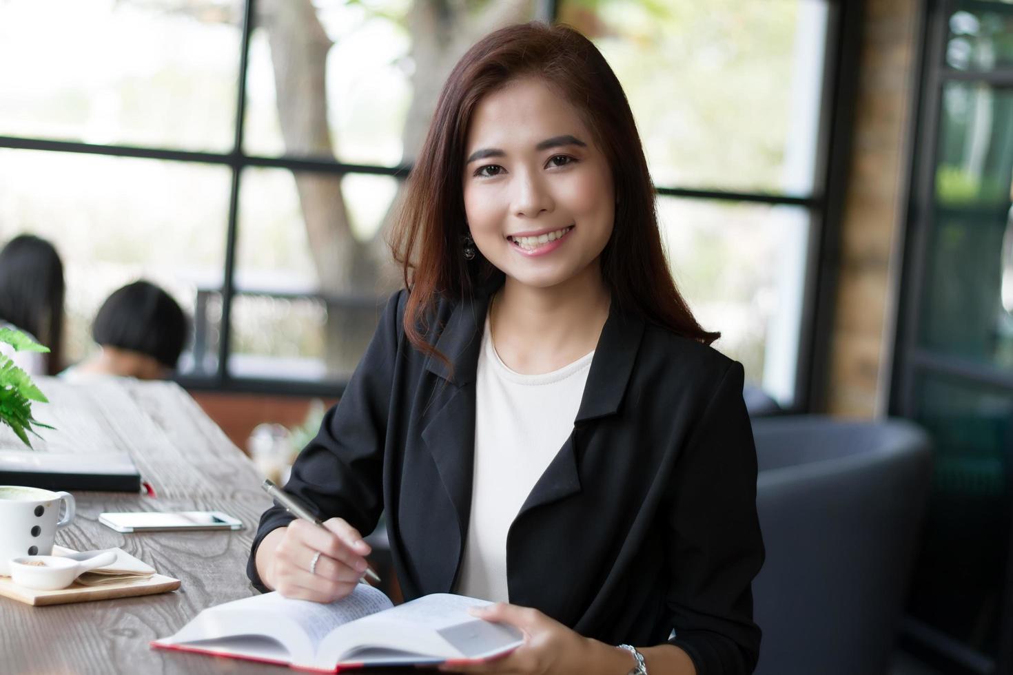 empresária asiática sorrindo segurando livro e caneta foto