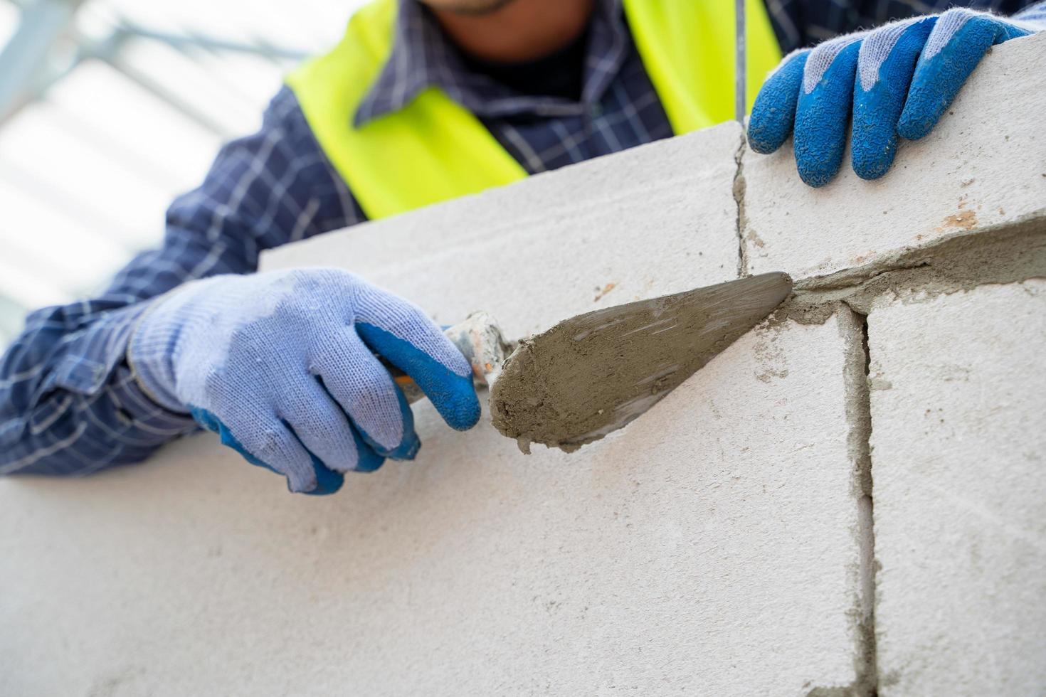 foto detalhada de um trabalhador da construção civil aplicando gesso na parede de tijolo