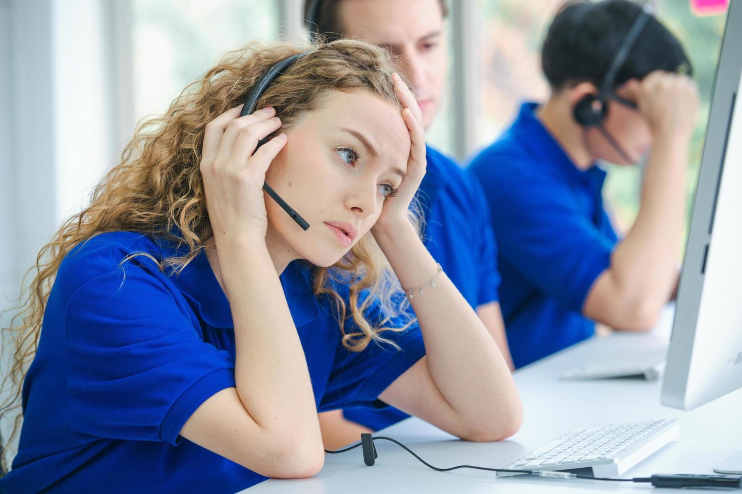 trabalhadores estressados do call center na frente dos computadores foto