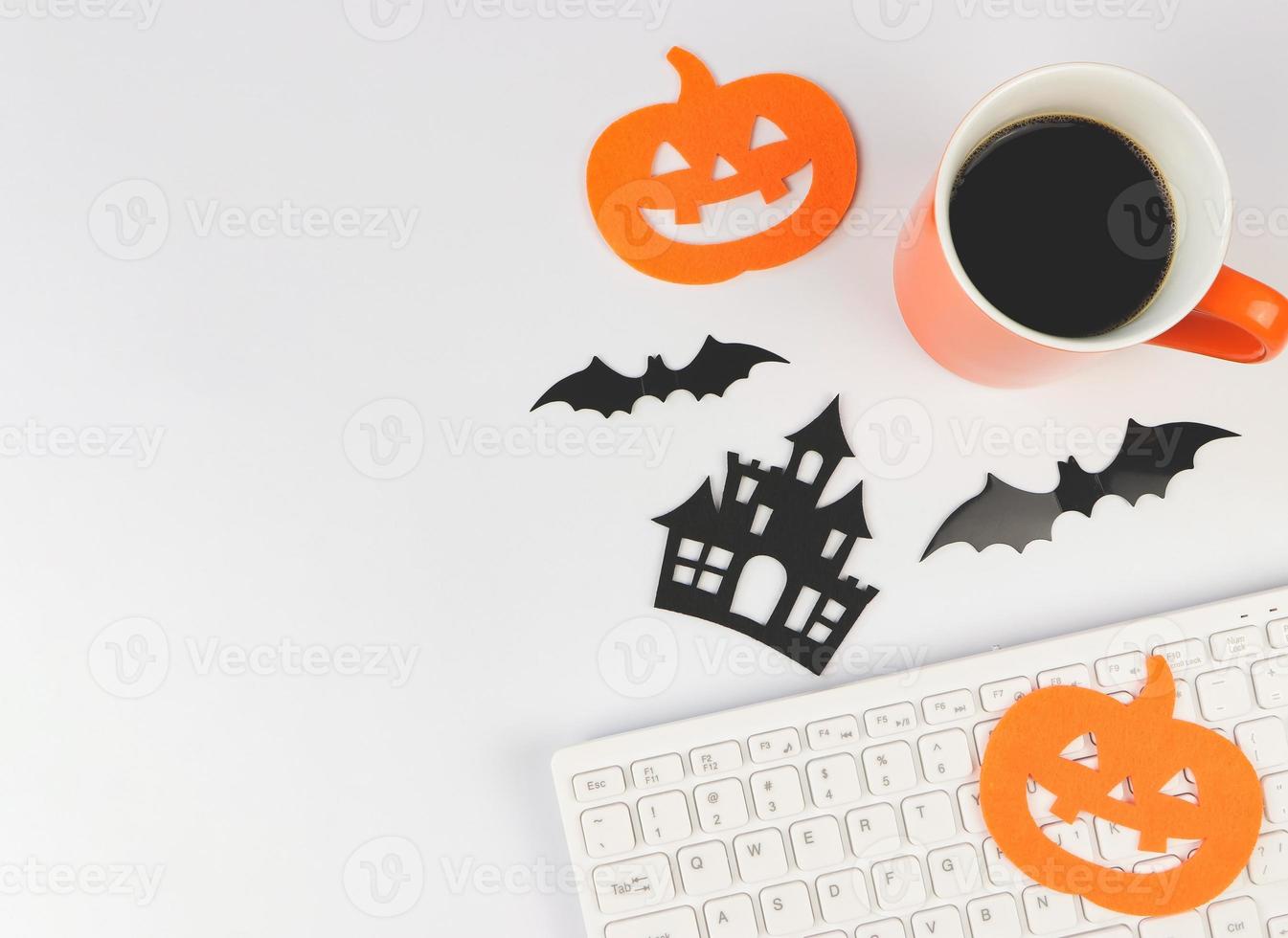 postura plana de teclado de computador, xícara de café, decorações de halloween, morcegos e abóbora em fundo branco com espaço de cópia. foto