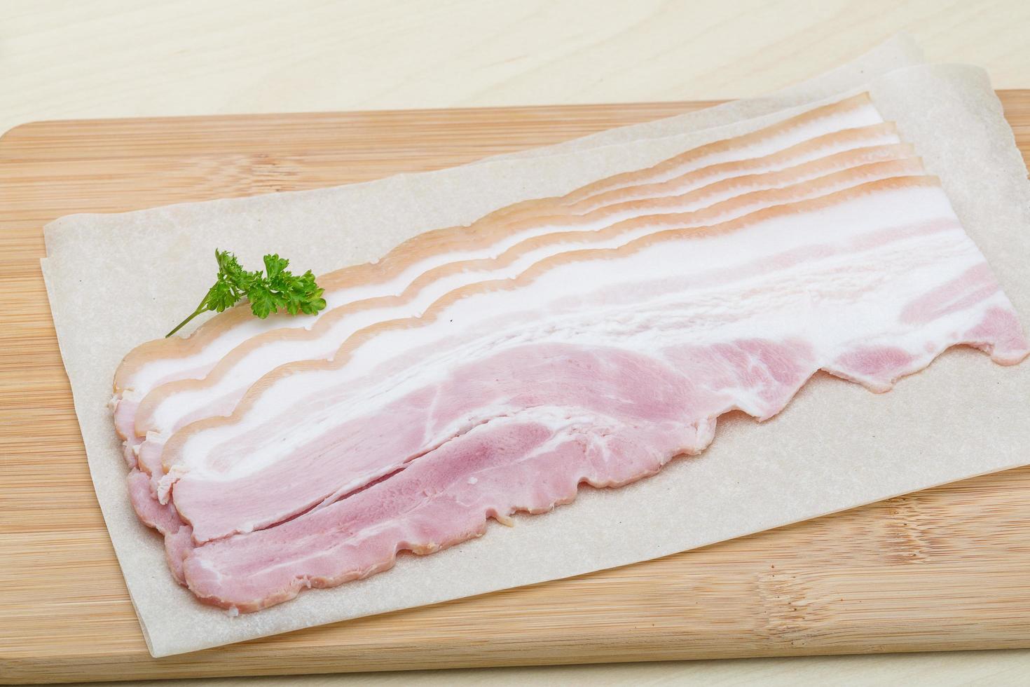 bacon cru na placa de madeira e fundo de madeira foto