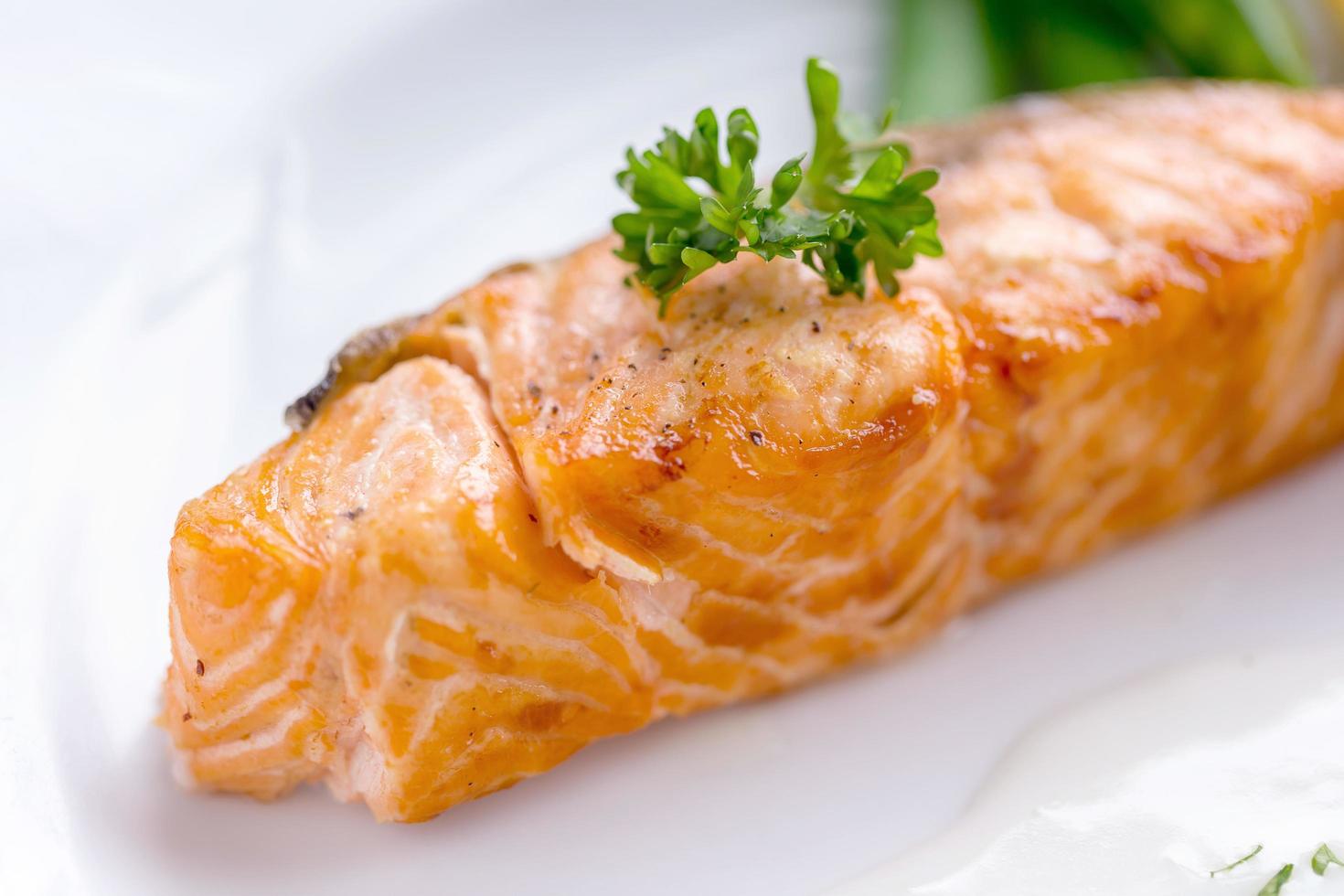 bife de salmão com molho branco em um prato branco foto