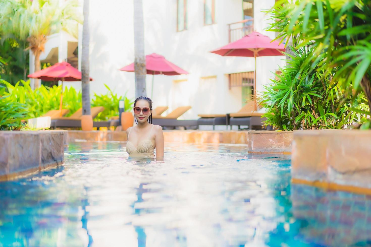 retrato bela jovem mulher asiática relaxar ao redor da piscina no hotel resort foto