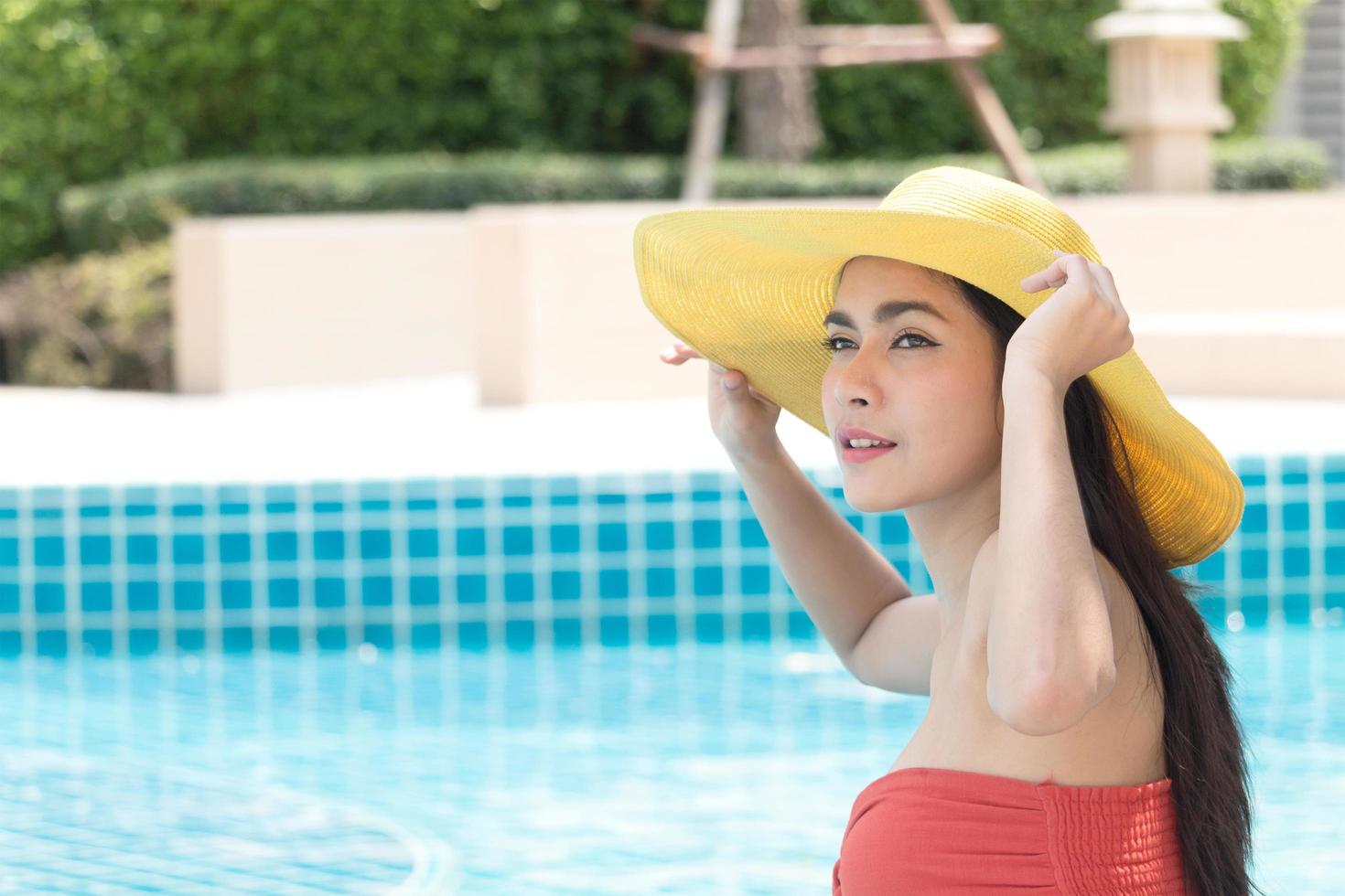 mulher asiática usando um chapéu amarelo na piscina foto